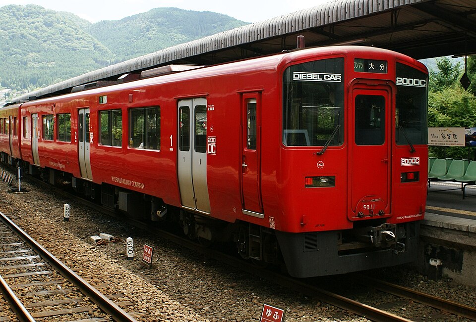 A bright red locomotive parked at a station platform.